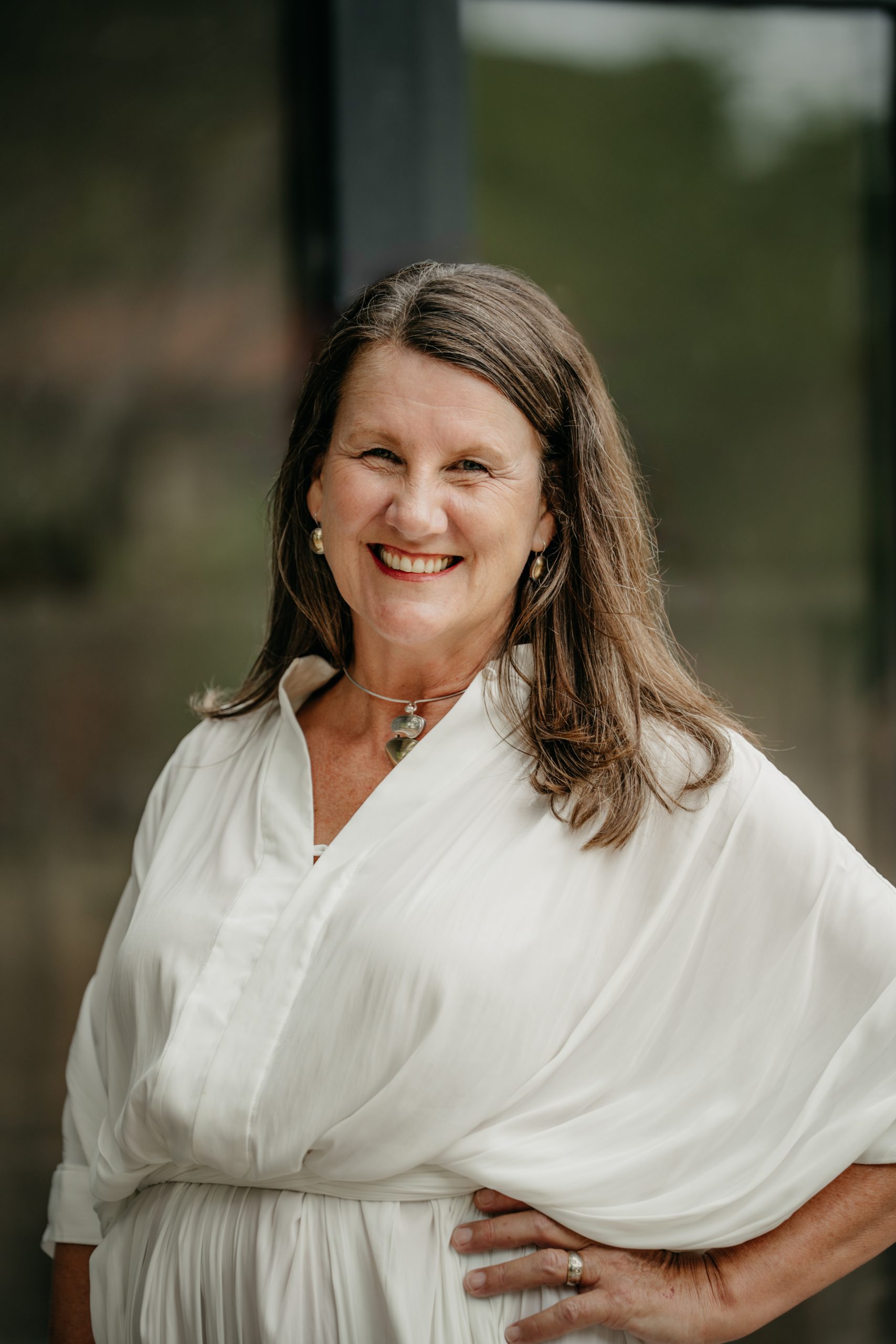 Rebecca Hannan, workplace mental health and wellbeing strategist, smiling in a white dress, championing positive workplace culture and psychological safety.